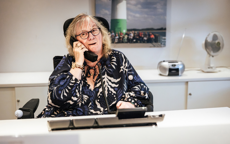 Eine Frau im Rollstuhl telefoniert am Empfang des Senator-Neumann-Hauses des Sozialkontors.