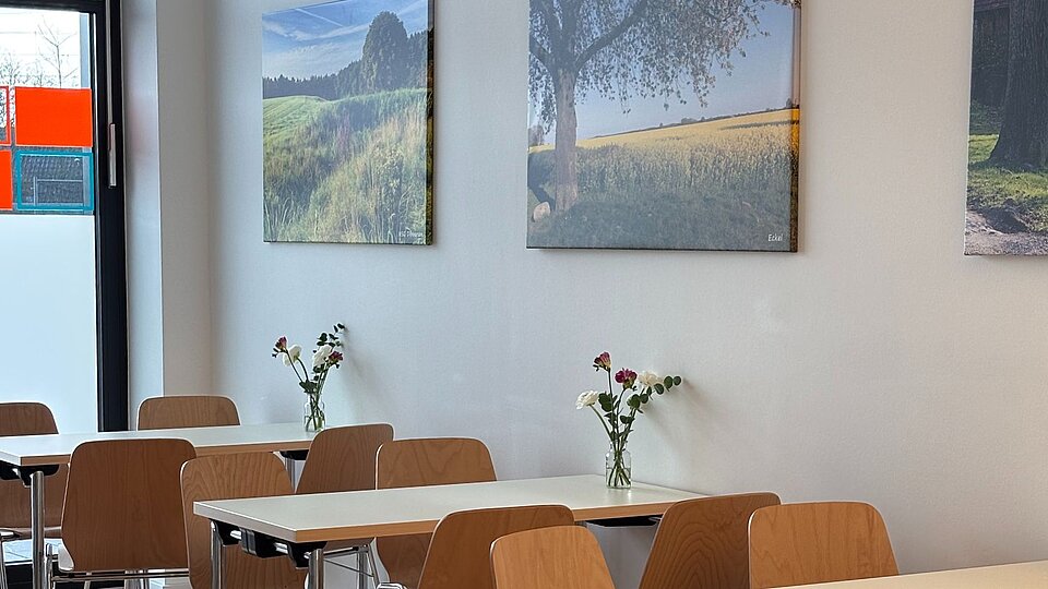 Innenraum der Assistenz, viele Tische mit Blumenvasen, Naturfotos hängen an der Wand