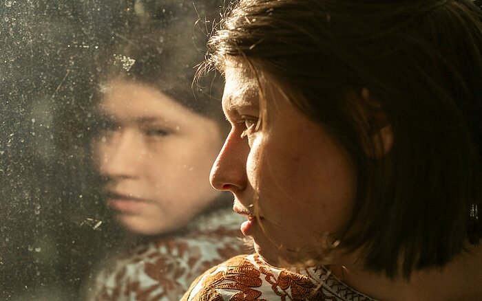 Die Hauptdarstellerin des Films Luisa blickt aus dem Fenster, in dem sich ihr Gesicht spiegelt. Foto: Daniel Pilar
