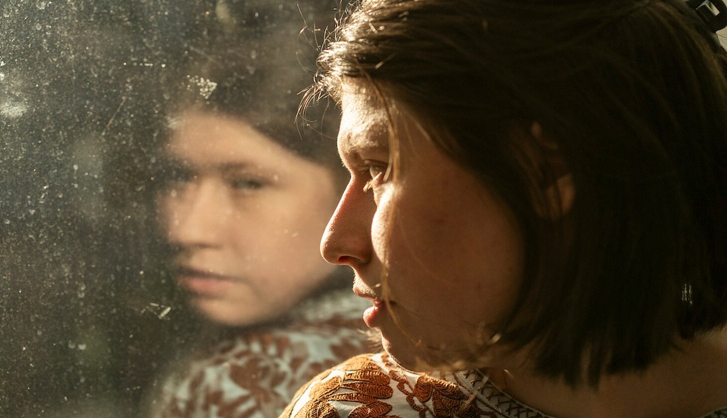 Die Hauptdarstellerin des Films Luisa blickt aus dem Fenster, in dem sich ihr Gesicht spiegelt. Foto: Daniel Pilar