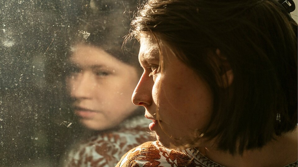 Die Hauptdarstellerin des Films Luisa blickt aus dem Fenster, in dem sich ihr Gesicht spiegelt. Foto: Daniel Pilar