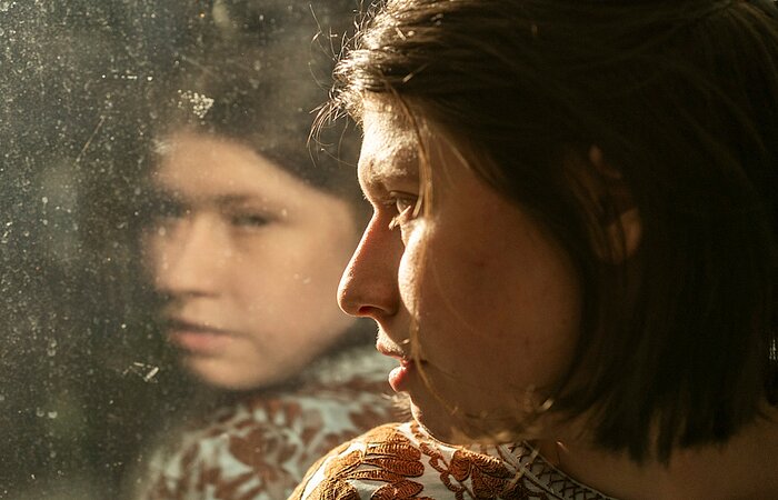 Die Hauptdarstellerin des Films Luisa blickt aus dem Fenster, in dem sich ihr Gesicht spiegelt. Foto: Daniel Pilar
