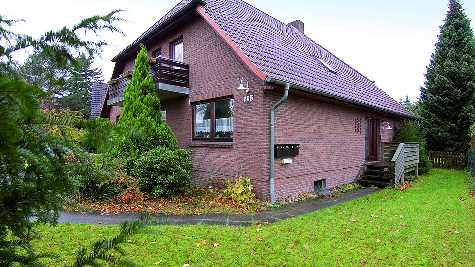 Einfamilienhaus, umgeben von Rasen und Bäumen