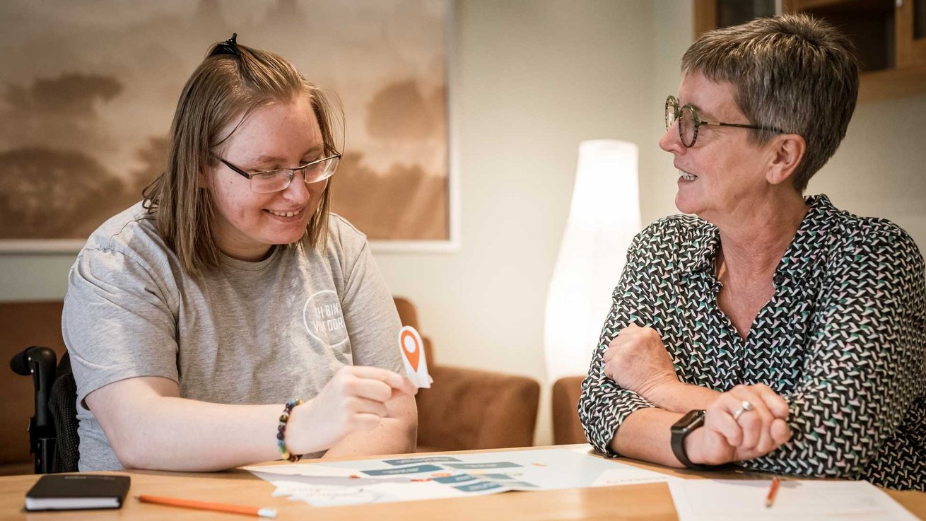 Zwei Frauen sitzen an einem Tisch und unterhalten sich
