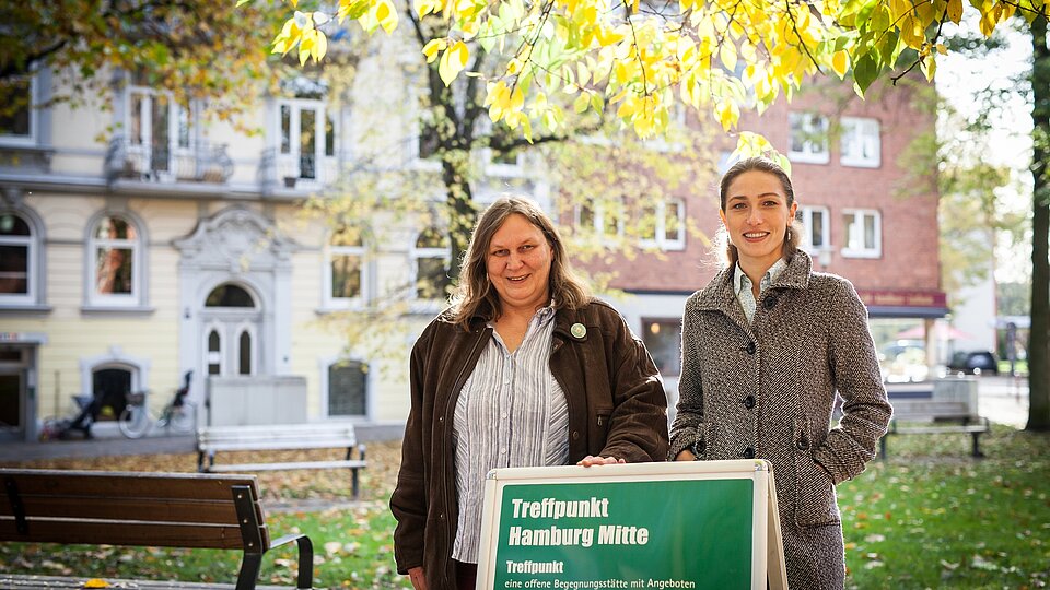 Im Freien, zwei Frauen stehen hinter einem Aufsteller