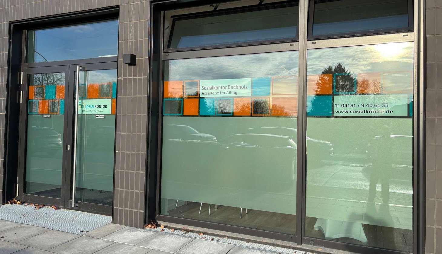 Außenansicht der Assistenz in Buchholz, große Fensterfront mit Sozialkontor-Schildern