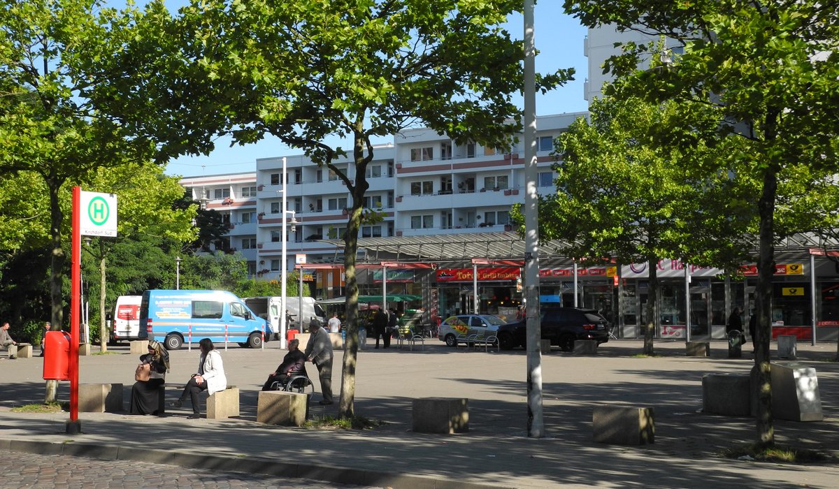 In der Nachbarschaft. Marktplatz mit Bushaltestelle und Geschäftszeile.
