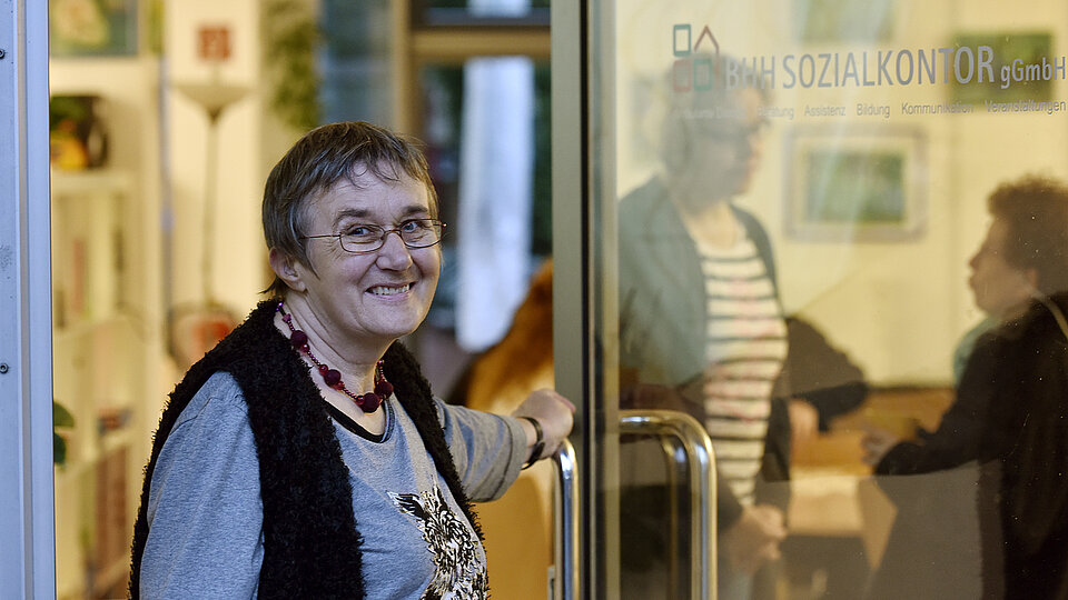 Ältere Frau öffnet eine Glastür