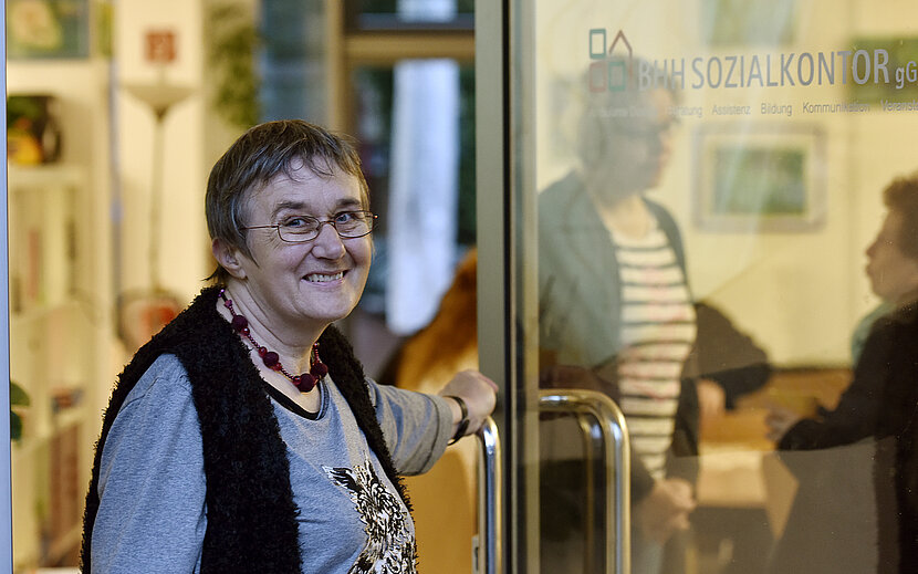 Ältere Frau öffnet eine Glastür