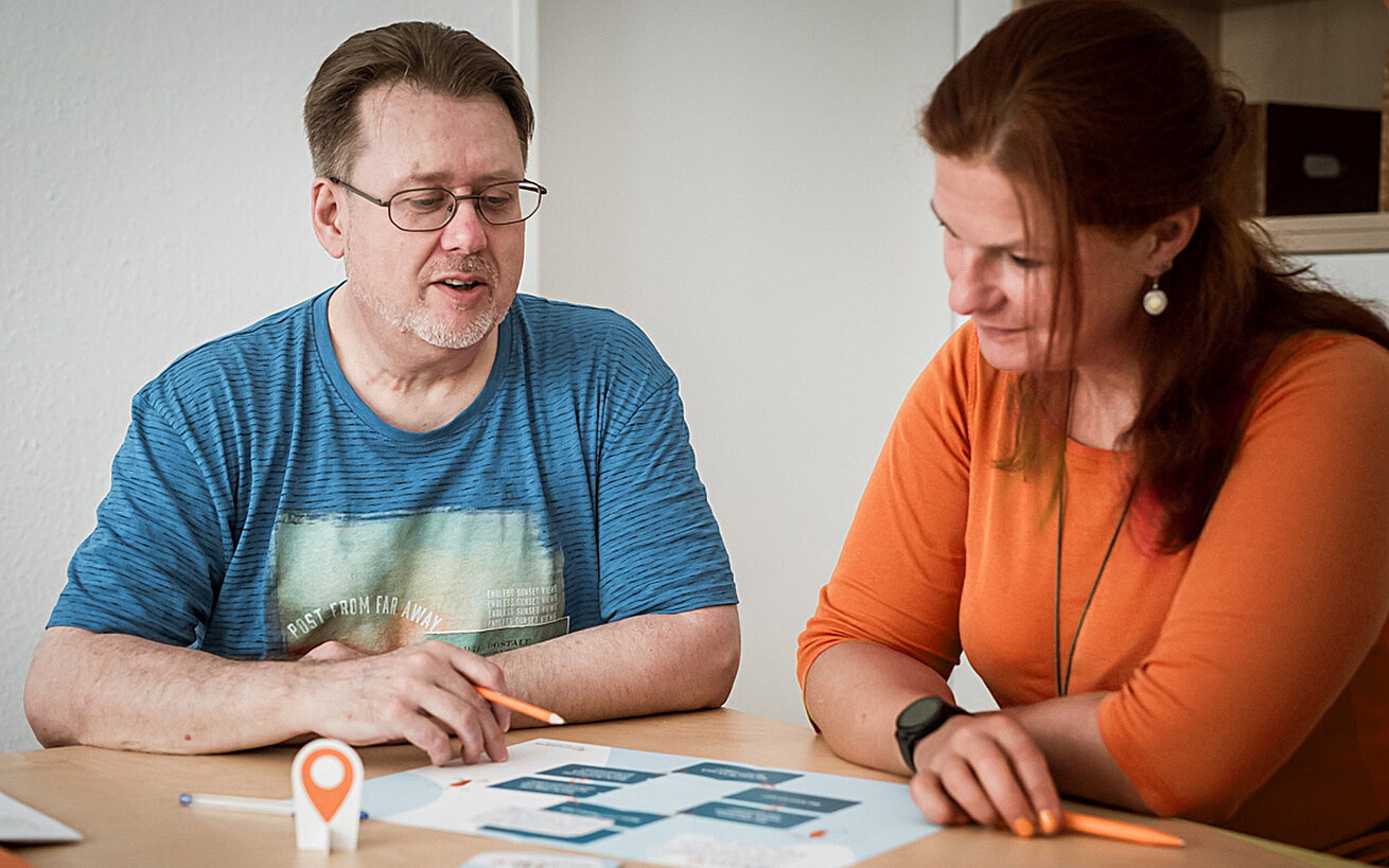 Ein Mann und eine Frau sitzen an einem Tisch und schauen auf eine Grafik