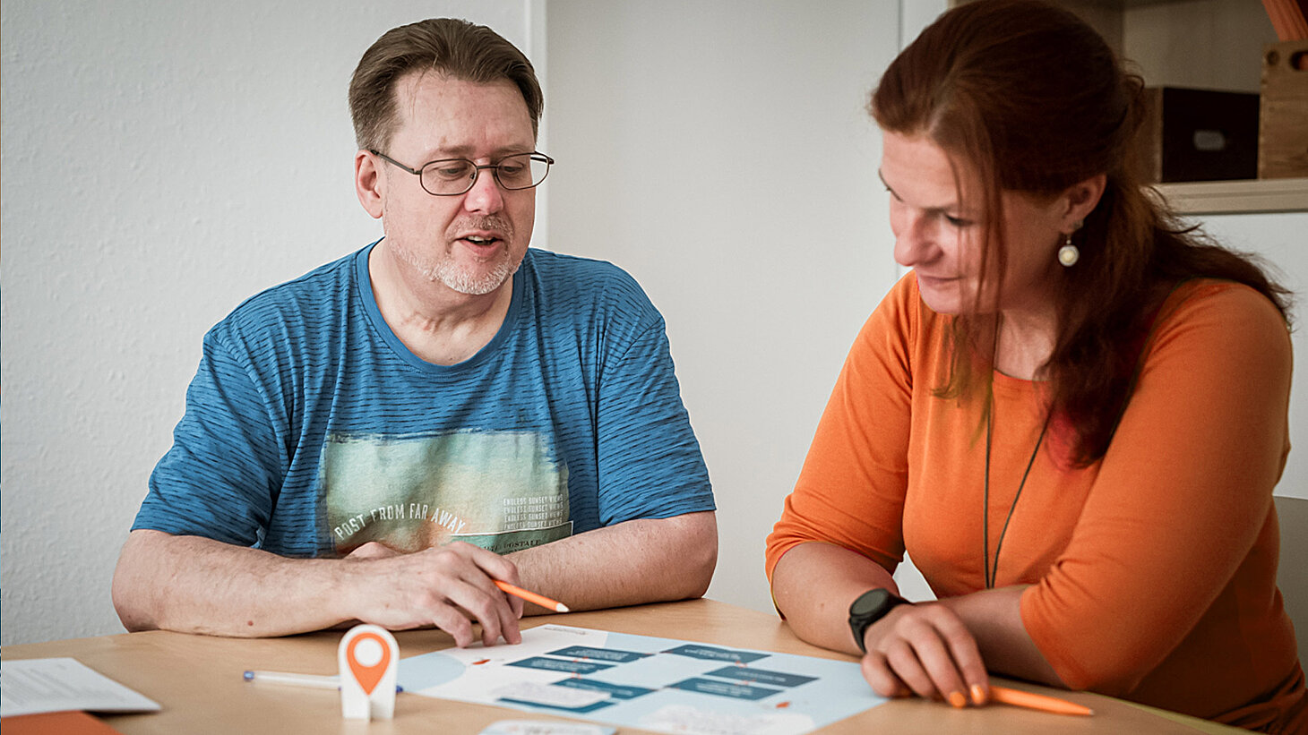 Ein Mann und eine Frau sitzen an einem Tisch und schauen auf eine Grafik