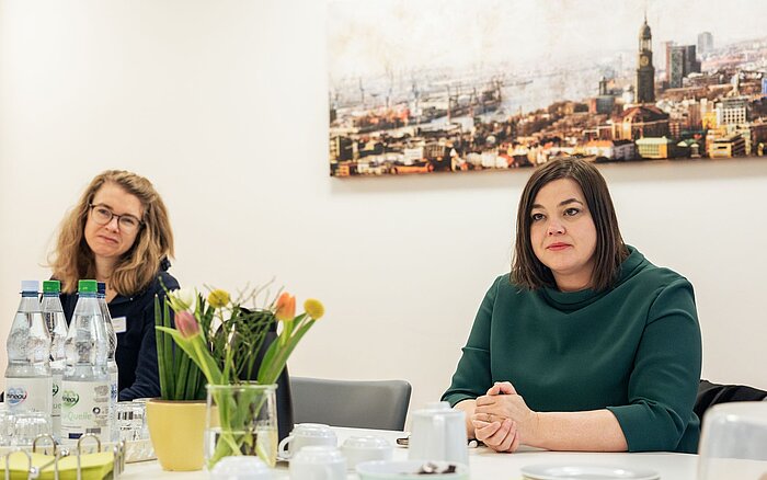 Hamburgs Zweite Bürgermeisterin Katharina Fegebank (rechts) sitzt an einem Tisch, neben ihr Britt Viemann (links), die Mietersprecherin von Wohnen mit Assistenz Klotzenmoor, einem Wohn-Angebot des Sozialkontors