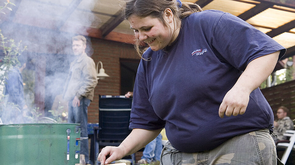 Auf einer Terrasse, junge Frau an einem Grill