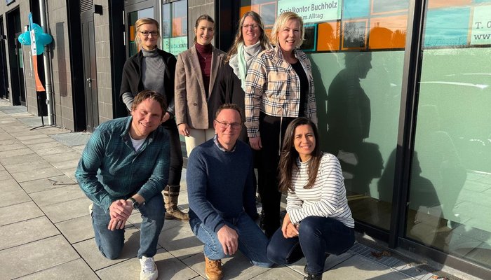 Das Team der Assistenz posiert draußen vor der Glasfront