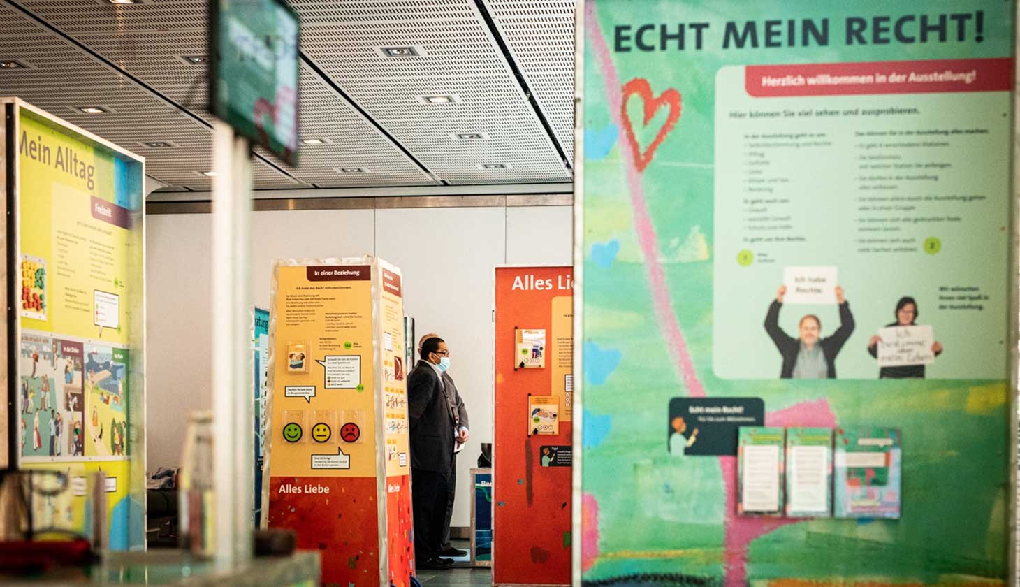 Eine Gruppe von Menschen steht vor einer Plakatausstellung mit Bannern mit der Aufschrift 