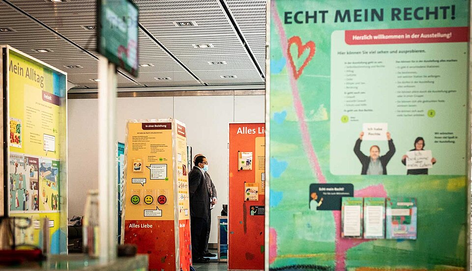 Eine Gruppe von Menschen steht vor einer Plakatausstellung mit Bannern mit der Aufschrift 