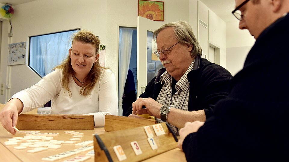 Drei Personen spielen ein Spiel an einem Tisch