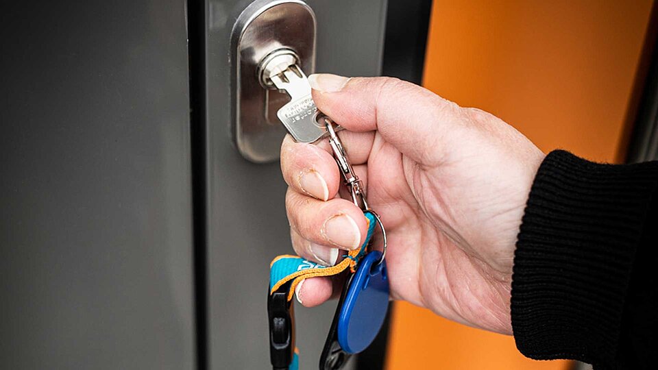 Hand mit Schlüssel, die Tür aufschließt
