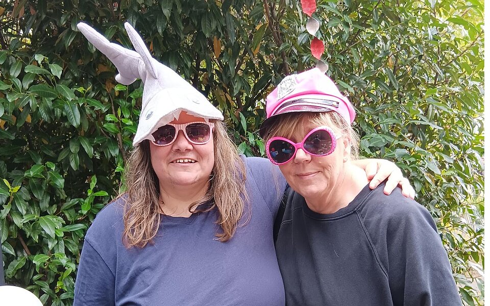 Zwei Frauen mit lustigen Hüten und Sonnenbrillen bei der Feier zu 20 Jahren Wohnen mit Assistenz in Farmsen-Berne und den Walddörfern.