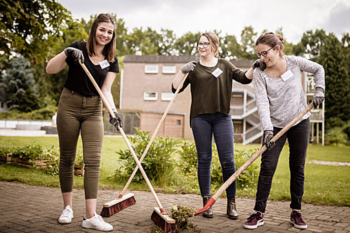 Drei Frauen im Garten beim Fegen