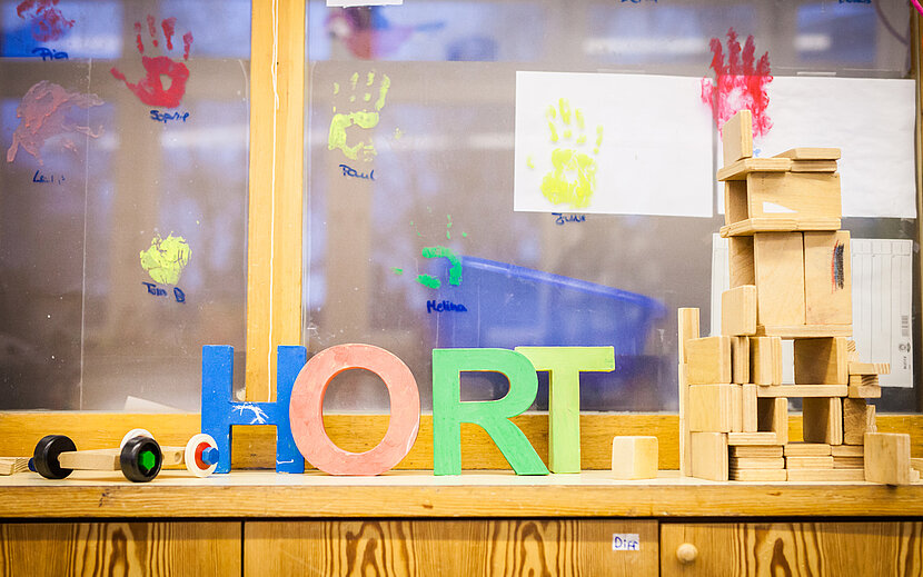 Im Hort. Eine Fensterbank, auf der bunte Holzbuchstaben stehen, die das Wort Hort bilden.