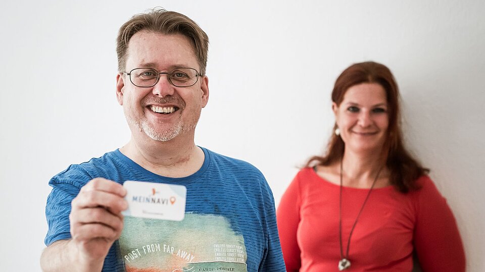 Ein Mann und eine Frau, der Mann zeigt eine Karte in die Kamera wo 