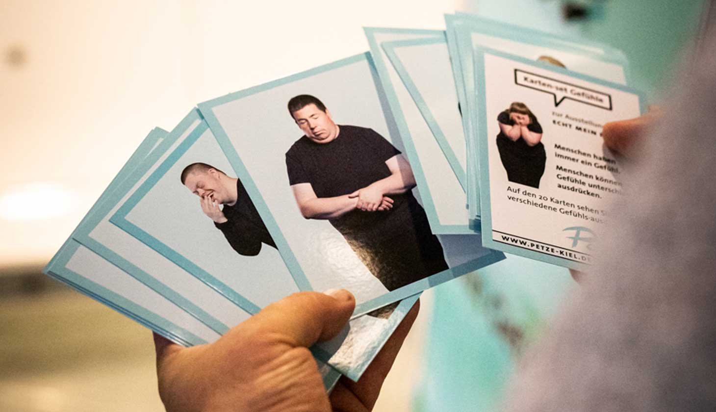 Eine Person hält einen Satz Karten mit Bildern von Menschen hoch.