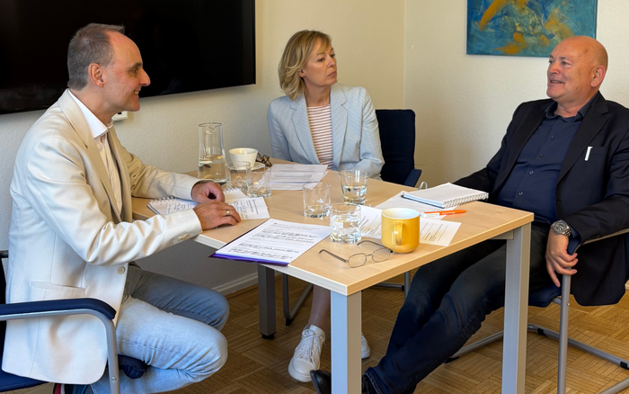Von links: Michael Wild, Gaby Klaas, Kay Nernheim sitzen an einem Tisch in einem Büro und unterhalten sich (Foto: Sozialkontor)