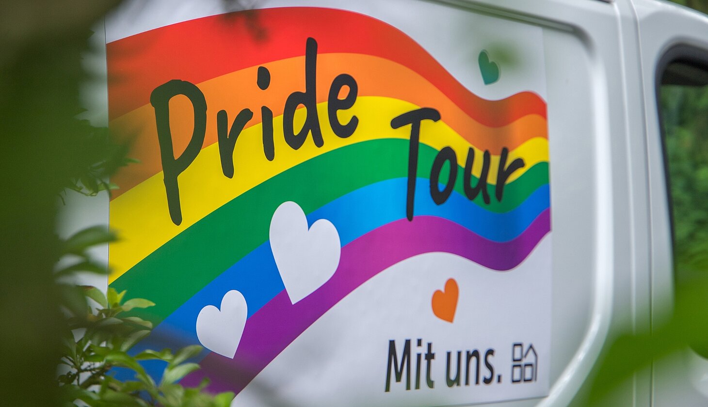 Detailaufnahme des Pride-Tour-Logos auf dem Transporter des Sozialkontors. Regenbogenfarben, Herzsymbole und der Schriftzug „Pride Tour“ stehen für Vielfalt und Akzeptanz.