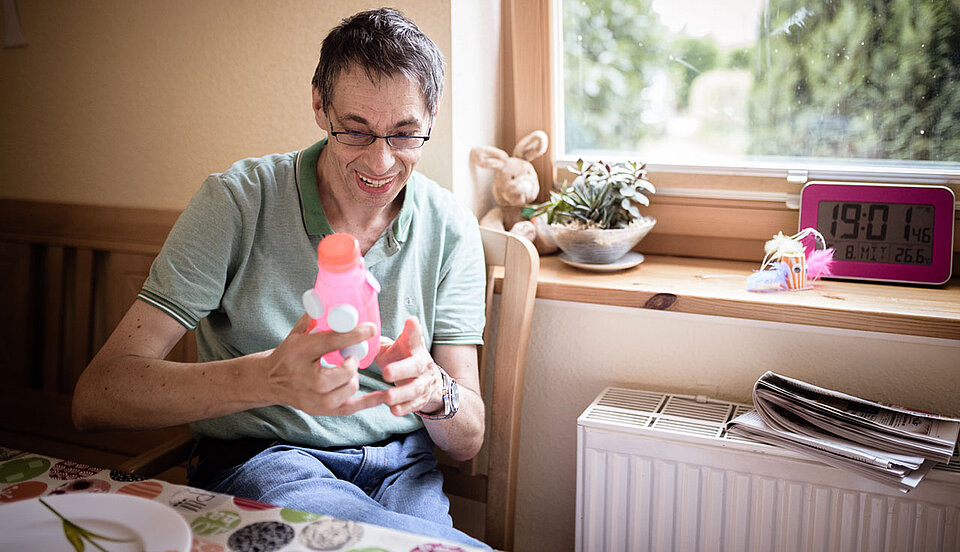 Ein Mann sitzt an einem Tisch, mit Plastikschwein