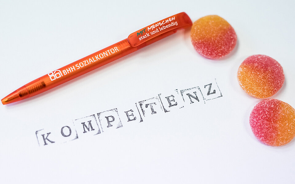 Zettel mit Druckbuchstaben Kompetenz und Bonbons